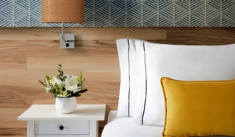 Family Room white bedside table with fresh flowers, a wooden headboard, and patterned blue wallpaper at Tivoli Alvor Algarve by Kenwood Travel