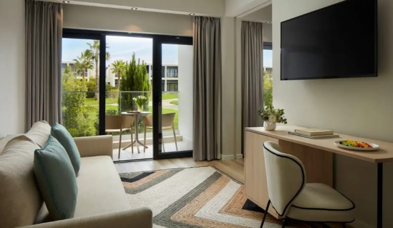 Premium Suite bedroom living room with desk, wall-mounted TV, and private terrace at Tivoli Alvor Algarve by Kenwood Travel