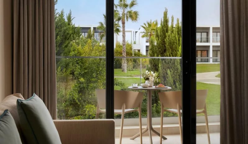 Premium Suite Private furnished balcony with views of lush green gardens, palm trees, and modern resort architecture at Tivoli Alvor Algarve by Kenwood Travel