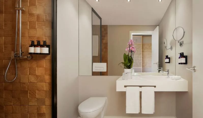 Premium Suite Bathroom walk-in rain shower with wood-textured tiling, a sleek vanity, and premium toiletries at Tivoli Alvor Algarve by Kenwood Travel
