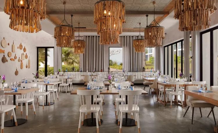 Roastic large driftwood chandeliers, white modern chairs, and floor-to-ceiling windows at Tivoli Alvor Algarve by Kenwood Travel
