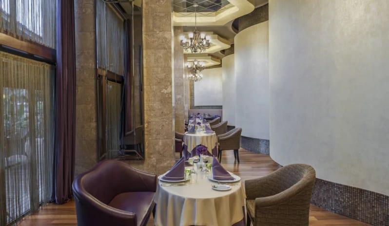 Finesse Indian Restaurant purple velvet seating, tiered chandeliers, and curved white walls at Hilton Dalaman Sarigerme Resort & Golf by Kenwood Travel