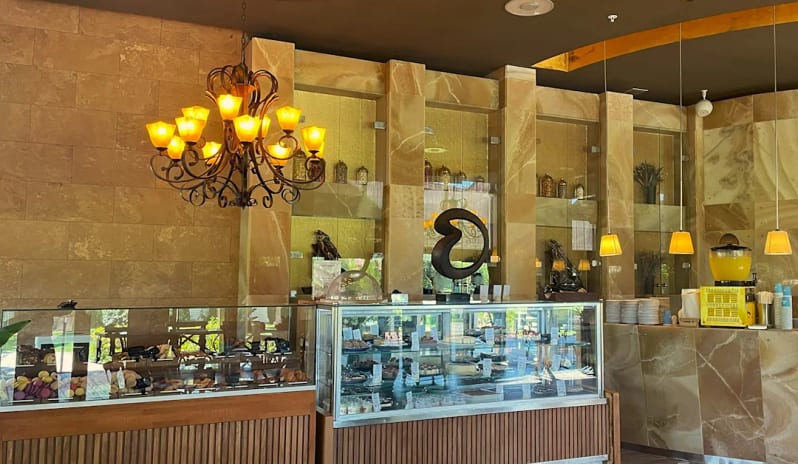Macaron Patisserie glass display cases filled with pastries and ornate gold chandeliers at Hilton Dalaman Sarigerme Resort & Golf by Kenwood Travel