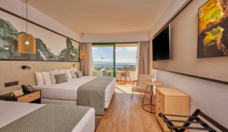 Double Side Ocean View Modern hotel double room interior featuring twin beds, light wood furniture, and a private balcony with an ocean view at Dreams Lanzarote Playa Dorada Resort & Spa by Kenwood Travel
