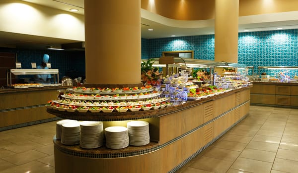 Main Restaurant Gourmet salad station at a resort restaurant with a chef in the background and organized stacks of white platesat Xanadu Island by Kenwood Travel