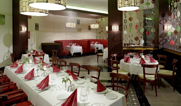El Toro à la Carte Restaurant Modern restaurant dining room design showing decorative hanging glass circle partitions, modern pendant lighting, a long dining table, and red semi-circular booths at Xanadu Island by Kenwood Travel