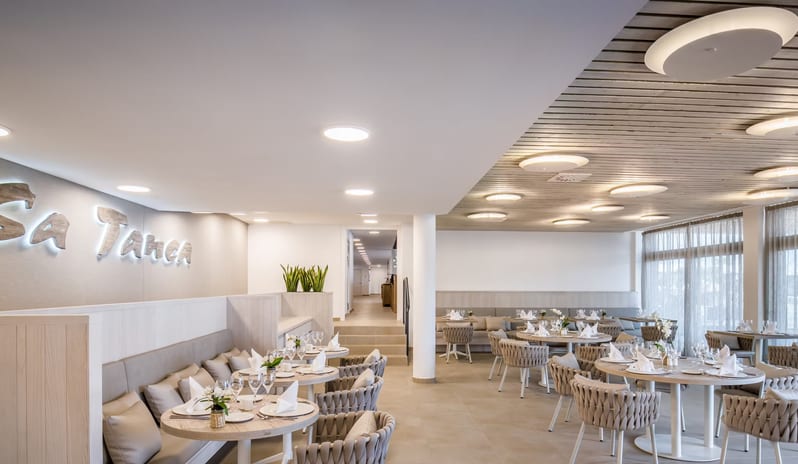 Sa Tanca Restaurant Modern restaurant interior design with slatted wood ceilings, circular recessed lighting, and built-in banquette seating at Barcelo Nura by Kenwood Travel