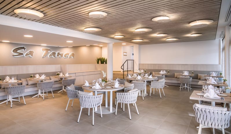 Sa Tanca Restaurant Modern restaurant interior design with slatted wood ceilings, circular recessed lighting, and built-in banquette seating at Barcelo Nura by Kenwood Travel
