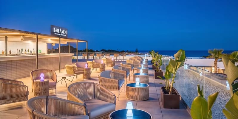 B-Heaven Rooftop Bar & Lounge modern wicker seating, glowing table lamps, and a panoramic ocean view at Barcelo Nura by Kenwood Travel