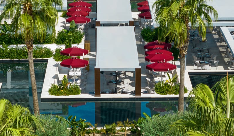 Dama Dama featuring white tables under red umbrellas and white pergolas next to a swimming pool at Grecotel LUXME Dama Dama by Kenwood Travel