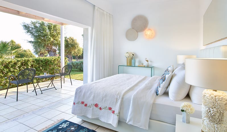 LUX ME Family Bungalow Pool side white bed with floral embroidery and a private walk-out terrace with garden seating at Grecotel LUXME Dama Dama by Kenwood Travel