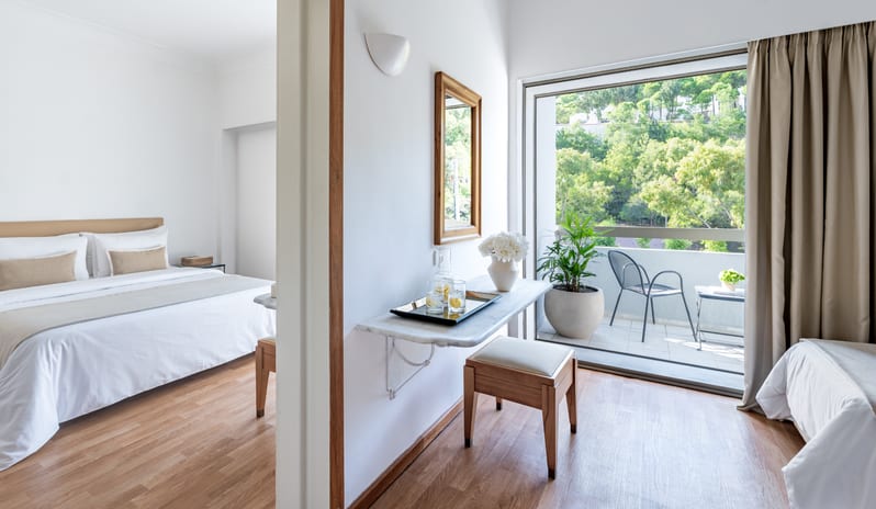 Premier Family Guestroom Inland View a bright inland view, white bedding, and a private balcony overlooking lush greenery at Grecotel LUXME Dama Dama by Kenwood Travel