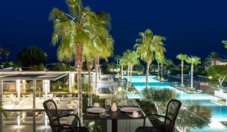 The Rose illuminated swimming pools and palm trees in Rhodes, Greece at Grecotel LUXME Dama Dama by Kenwood Travel
