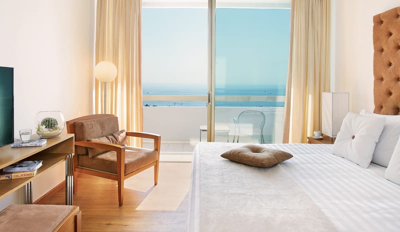 LUX ME Family Guestroom Sea View private balcony with sea views, a comfortable armchair, and modern interior design at Grecotel LUXME Dama Dama by Kenwood Travel