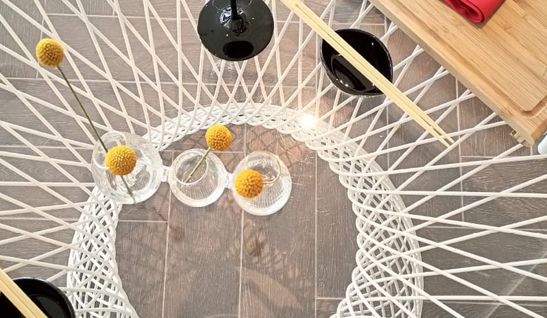 Asiana Grecotel LUXME Dama Dama Asiana black wine glasses, red napkins, and yellow billy button flowers on a white geometric table -Kenwood Travel at Grecotel LUXME Dama Dama by Kenwood Travel