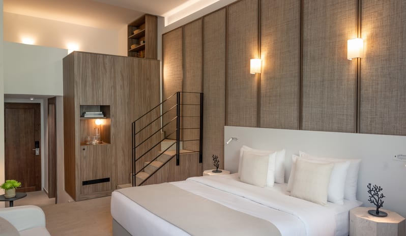 Premier Loft Family Guestroom neutral color palette, wooden stairs leading to a loft, and luxury minimalist decor at Grecotel LUXME Dama Dama by Kenwood Travel