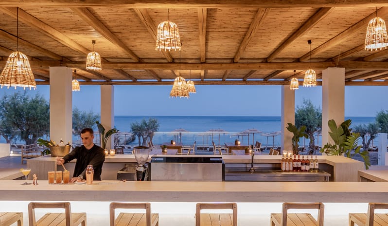 Beach Club professional bartender preparing cocktails at the backlit white marble bar at Grecotel LUXME Dama Dama by Kenwood Travel