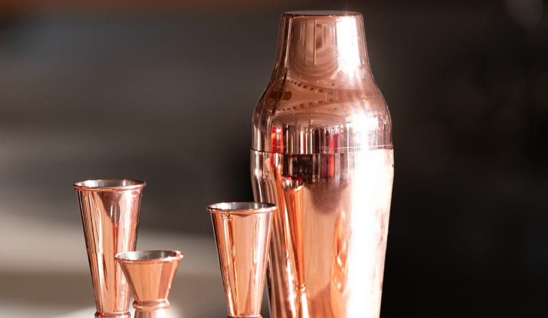 Lobby Bar Close-up of elegant rose gold cocktail shaker and professional jiggers on a marble bar top at Grecotel LUXME Dama Dama by Kenwood Travel
