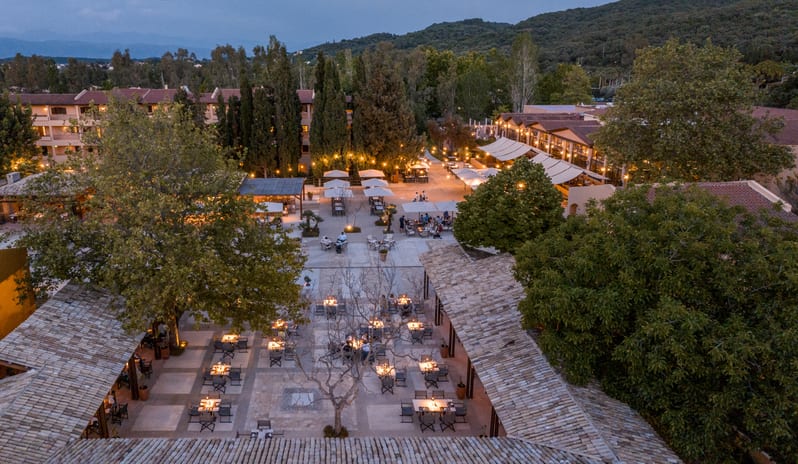 Asiana beautifully lit dining tables surrounded by lush trees and resort buildings at Grecotel LUXME Costa Botanica by Kenwood Travel