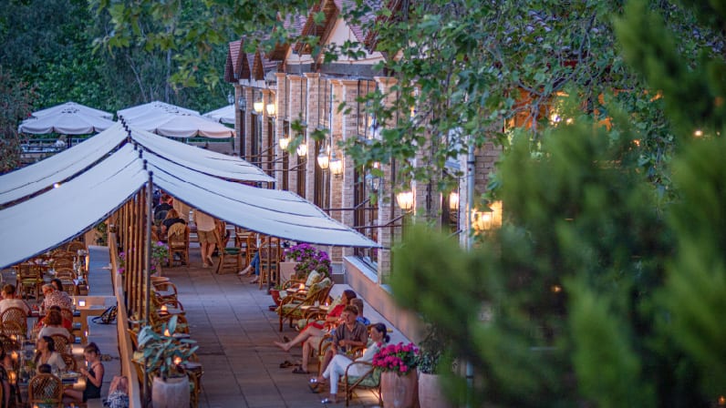 Bar Centrale Warmly lit evening terrace lounge surrounded by greenery at a luxury resort at Grecotel LUXME Costa Botanica by Kenwood Travel