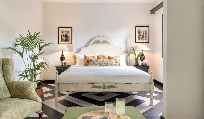 Family Suite at Yuccas Residence Veranda Sharing Pool Elegant boutique hotel family suite with a king-size bed, symmetry bedside lamps, green armchair, and fresh lemonade on the coffee tabl at Grecotel LUXME Costa Botanica by Kenwood Travel