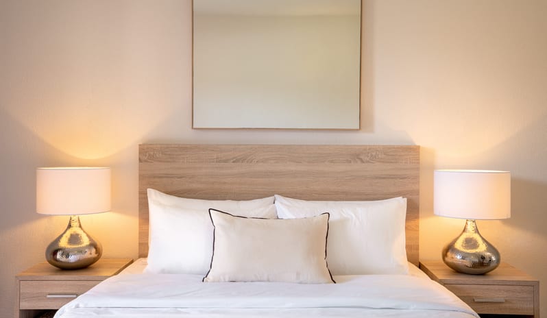 Play Room Suite light wood headboard, white bedding, and elegant bedside lamps at Grecotel LUXME Costa Botanica by Kenwood Travel