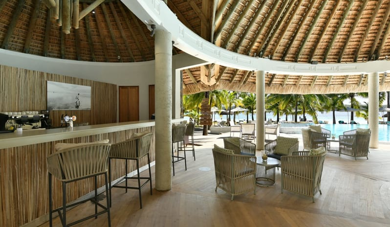 Sirius Bar Open-air beachfront resort bar with thatched roof, comfortable lounge seating, and an outdoor swimming pool surrounded by palm trees at Shandrani for 2 by Kenwood Travel