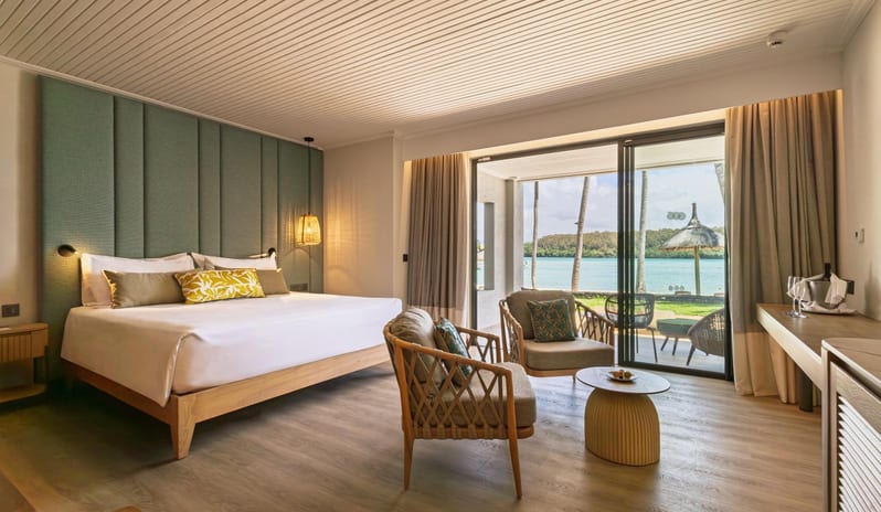 Beach View Room  king bed, green upholstered headboard wall, and sliding glass doors opening to a scenic beachfront patio and ocean view at Shandrani for 2 by Kenwood Travel