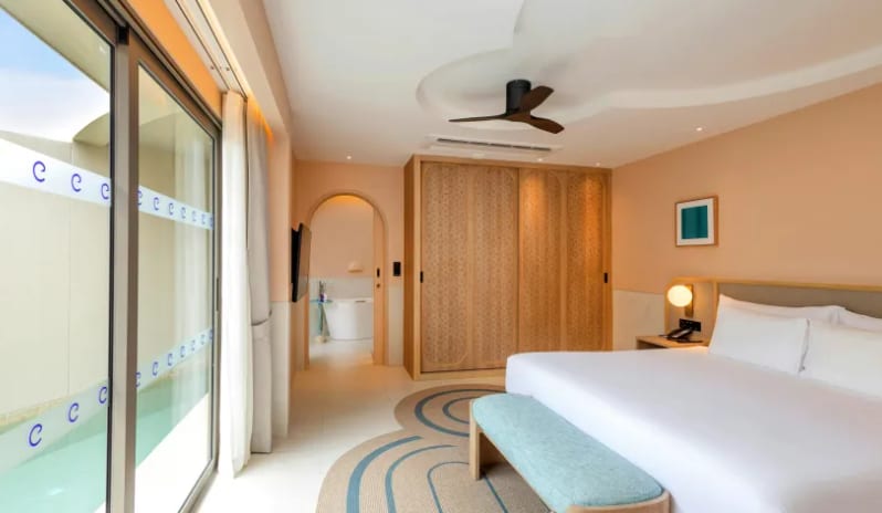 One Bedroom Pool Villa king bed, custom wood wardrobe, and sliding glass doors opening directly to a private swimming pool at Centara Karon Villas Phuket by Kenwood Travel