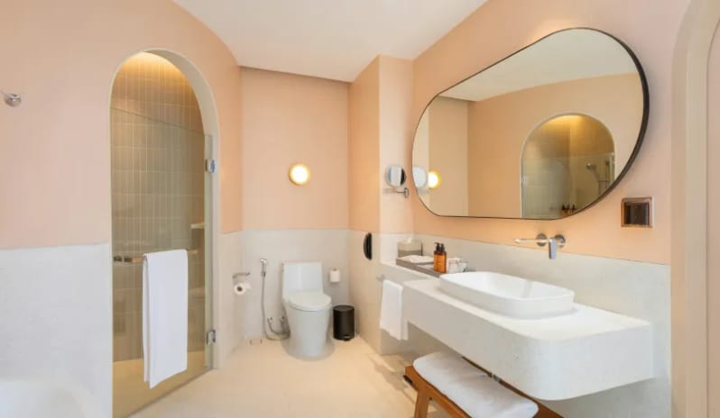Three Bedroom Pool Villa bathroom featuring a modern floating vanity with a vessel sink, a large oval mirror, and an arched walk-in glass shower at Centara Karon Villas Phuket by Kenwood Travel