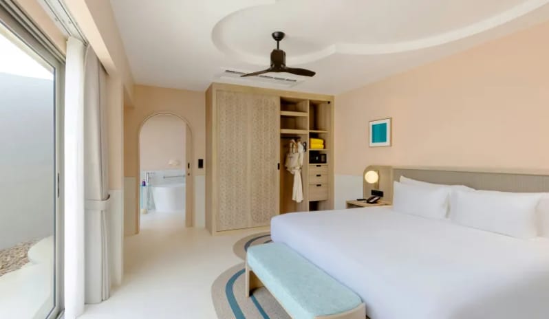 One Bedroom Private Villa king bed, open wooden wardrobe with robes, ceiling fan, and view of an ensuite bathroom with tub at Centara Karon Villas Phuket by Kenwood Travel