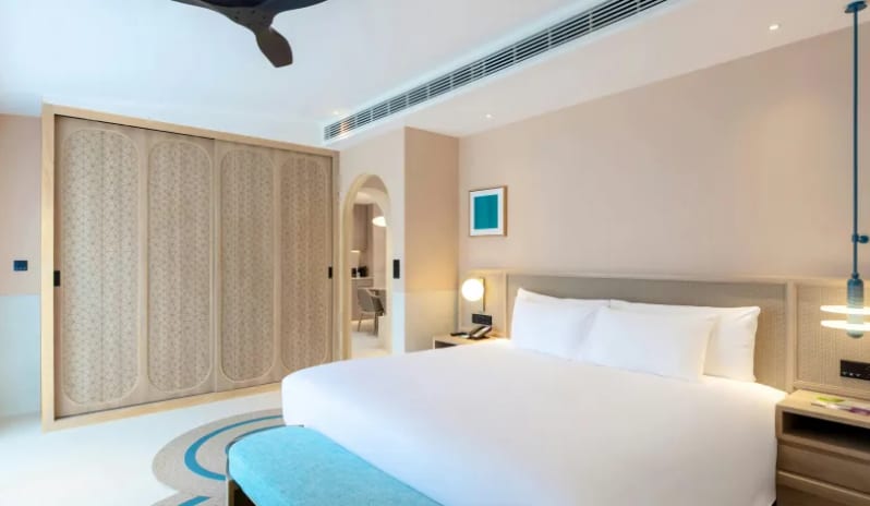 Three Bedroom Pool Villa Modern luxury three-bedroom pool villa master bedroom featuring a king bed, teal accents, and textured wooden wardrobe at Centara Karon Villas Phuket by Kenwood Travel