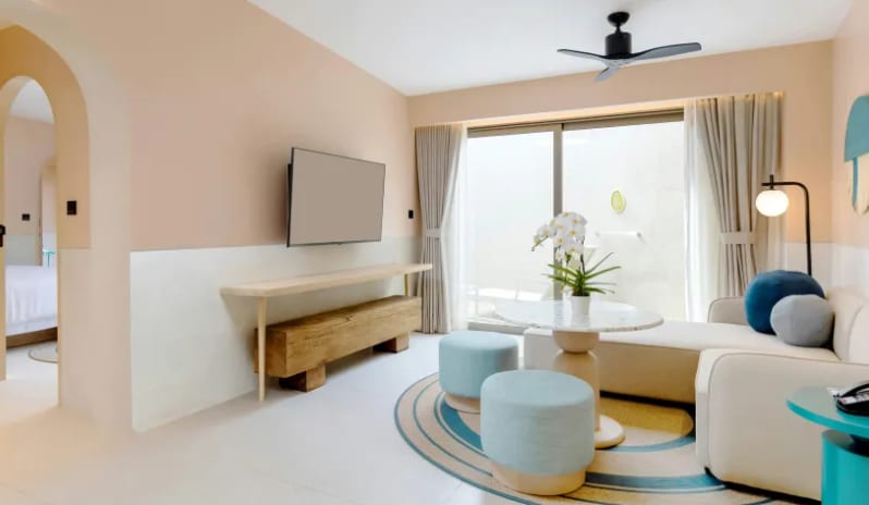Three Bedroom Pool Villa Luxury three-bedroom pool villa living room lounge with a sectional sofa, teal ottomans, a flat-screen TV, and sliding glass doors leading to a private outdoor space at Centara Karon Villas Phuket by Kenwood Travel