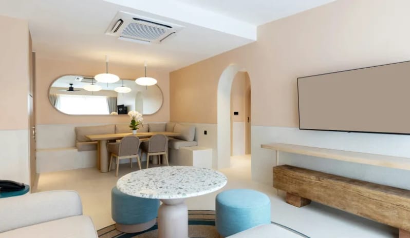 Three Bedroom Pool Villa Contemporary 3-bedroom villa open-concept lounge showing a flat-screen TV, wooden bench, terrazzo-top coffee table, and an adjacent built-in dining alcove at Centara Karon Villas Phuket by Kenwood Travel