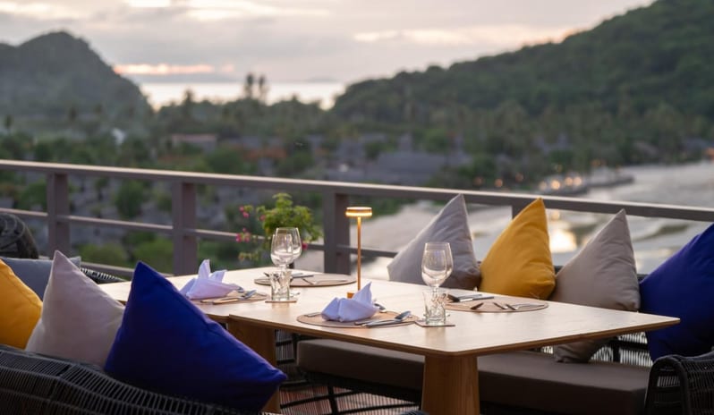 Jantra Bar Outdoor dining table with a scenic mountain and ocean backdrop at Jantra Bar at Centara Villas Phi Phi Island by Kenwood Travel