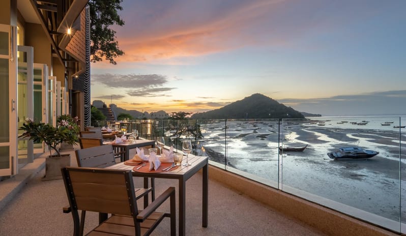 Maya Breeze Beachfront restaurant balcony dinner tables with wine glasses and sunset ocean views at Centara Villas Phi Phi Island by Kenwood Travel