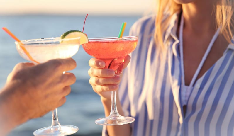 The Pool Deck Close up of two people toasting with colorful summer cocktails by the ocean at sunset at Centara Villas Phi Phi Island by Kenwood Travel