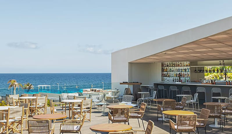 Lemon Fish Nikkei Sky Bar modern rooftop bar and restaurant terrace featuring woven chairs and wooden tables overlooking the blue ocean under a clear sky at Paradisus Gran Canaria by Kenwood Travel