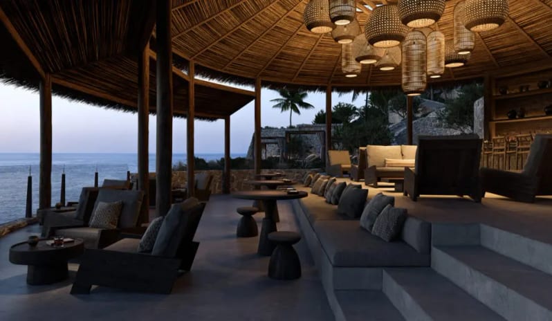 The Round Bar Luxury open-air resort lounge featuring woven pendant lights, comfortable grey seating, and a thatched roof overlooking the ocean at dusk at OKU Bodrum by Kenwood Travel