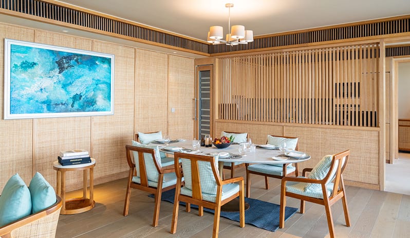 Three bedroom Beach Retreat with Private Pool Elegant indoor dining area of a luxury villa featuring a marble oval table, light wood paneling, a blue abstract painting, and contemporary seating at Kuda Villingili Resort Maldives by Kenwood Travel