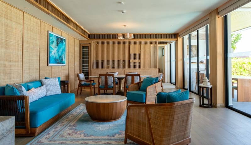Three bedroom Beach Retreat with Private Pool Spacious open-plan living and dining area in a luxury villa featuring bright blue sofas, wooden armchairs, a marble coffee table, and large glass doors leading to a terrace at Kuda Villingili Resort Maldives by Kenwood Travel