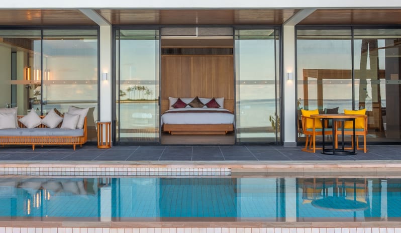 Two Bedroom Beach Villa with Private Pool Poolside terrace of a luxury tropical resort villa featuring floor-to-ceiling glass doors, outdoor lounge seating, and an ocean-view bedroom suite at Kuda Villingili Resort Maldives by Kenwood Travel