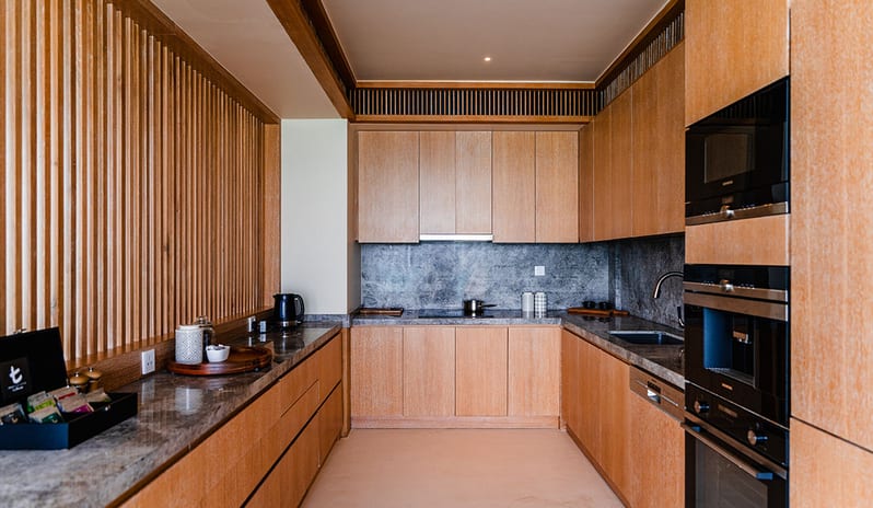 Three bedroom Beach Retreat with Private Pool Modern luxury villa kitchen featuring light wood cabinetry, grey marble countertops, integrated high-end appliances, and a minimalist wood-slat feature wall at Kuda Villingili Resort Maldives by Kenwood Travel