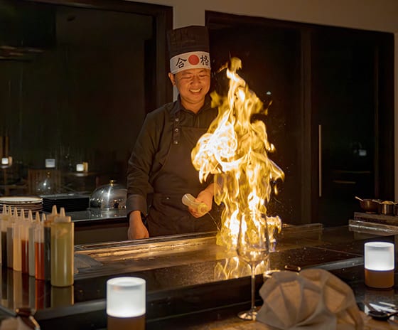 Teppanyaki by Mar-Umi chef creating a large dramatic flame on a flat-top grill during a live cooking performance at Kuda Villingili Resort Maldives by Kenwood Travel