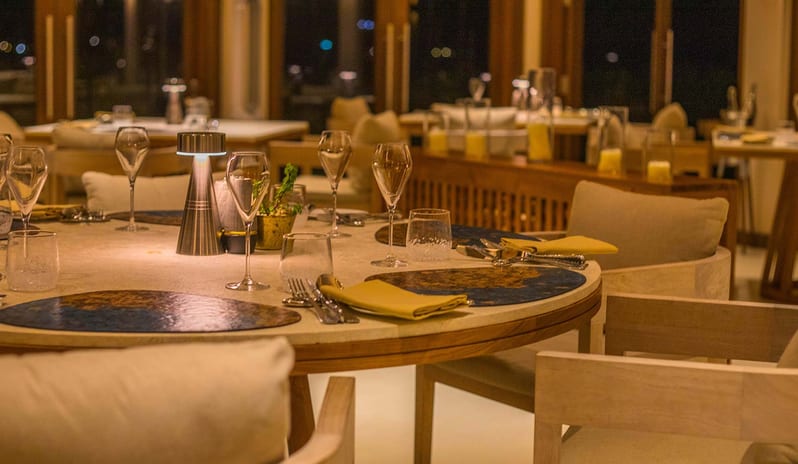 Ocean Luxury restaurant table setting with wine glasses and designer decor at night at Kuda Villingili Resort Maldives by Kenwood Travel