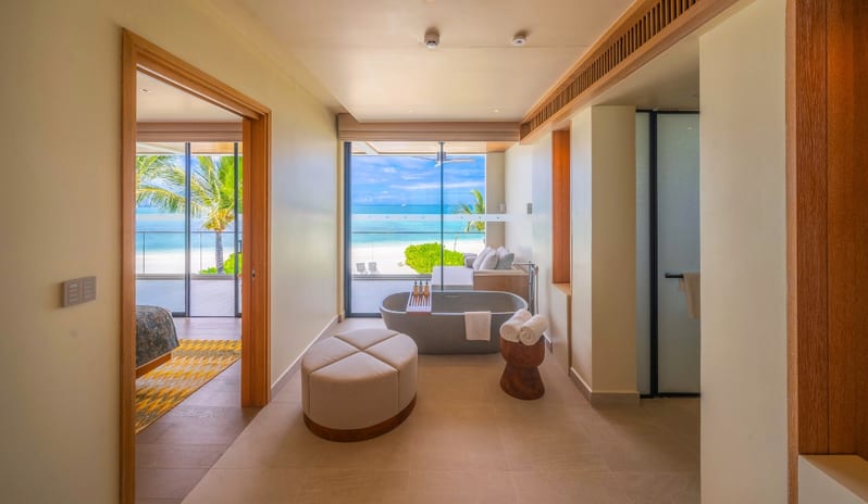 Two Bedroom Beach Residence with Private Pool freestanding stone bathtub, plush ottoman, and floor-to-ceiling windows overlooking a private balcony and the turquoise ocean at Kuda Villingili Resort Maldives by Kenwood Travel