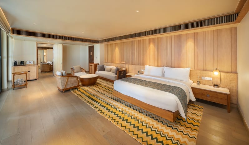 Two Bedroom Beach Villa with Private Pool Interior view of a luxury beach villa bedroom with modern wooden decor and seating area at Kuda Villingili Resort Maldives by Kenwood Travel