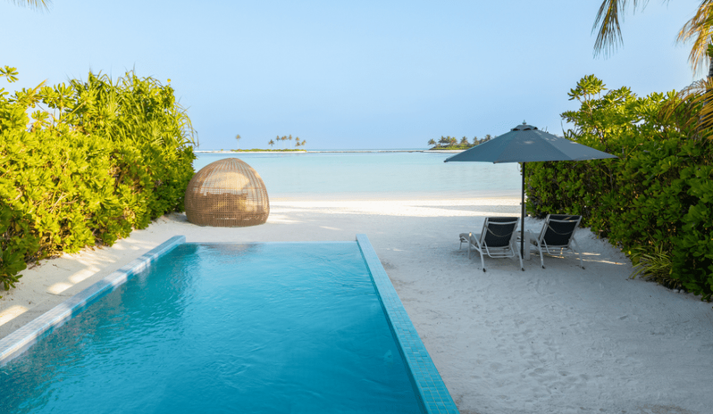 Sunrise Beach Villa with Private Pool Private turquoise infinity pool at a beach villa overlooking a white sand beach and calm ocean with distant palm islands at Kuda Villingili Resort Maldives by Kenwood Travel