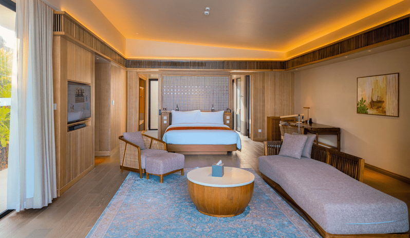Sunrise Beach Villa with Private Pool Luxury sunrise beach villa interior featuring a king-size bed, private lounge area with a blue patterned rug, and warm cove lighting at Kuda Villingili Resort Maldives by Kenwood Travel