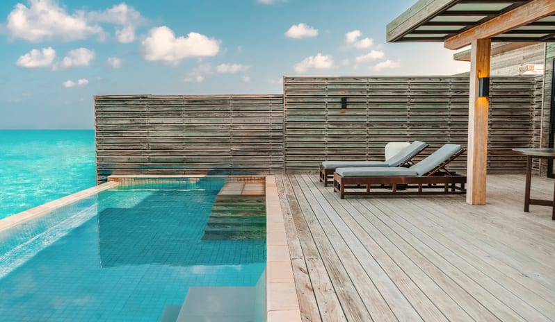 Sunrise Water Villa with Private Pool overwater villa terrace in the Maldives with an infinity plunge pool, wooden decking, and loungers offering unobstructed views of the tropical sea at Kuda Villingili Resort Maldives by Kenwood Travel